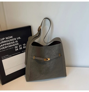 Detailed close-up of dark grey leather tote bag with unique gold metal buckle
