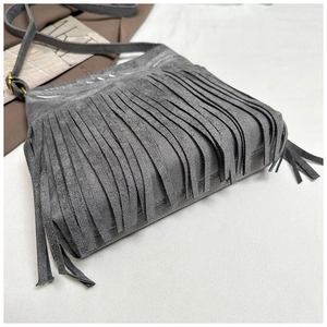 Detalle del bolso bandolera de ante sintético gris con flecos largos y herrajes dorados