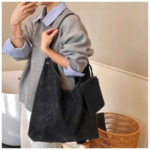 Detail of black suede tote bag with contrast stitching and small coin purse attached