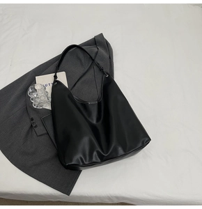 Détail du sac cabas noir avec coutures contrastées blanches sur blazer gris