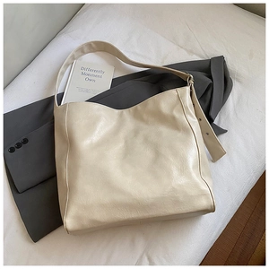 Close-up of cream PU leather tote bag featuring side metal eyelets and wrinkled texture