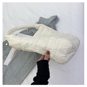 Detail of white quilted tote bag featuring soft pleated texture and square stitch pattern