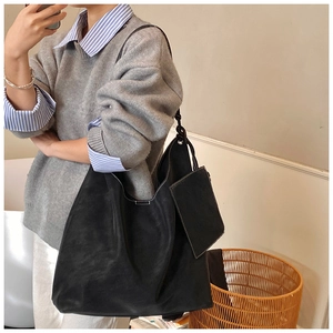 Detail of black suede tote bag with white contrast stitching and matching small pouch