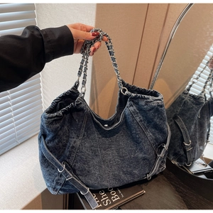 Detailed macro view of large washed denim tote bag with chain strap and vintage buckles