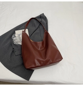 Détail du sac hobo en cuir marron foncé avec surpiqûres blanches et boucle en métal