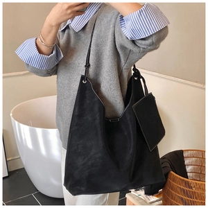 Detail of a black large tote bag with contrast stitching and a small detachable pouch
