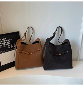 Close-up of matte leather bucket bag with elegant interlocking gold metal buckle detail