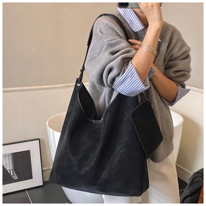 Detail view of black matte tote bag with contrast white stitching and small pouch