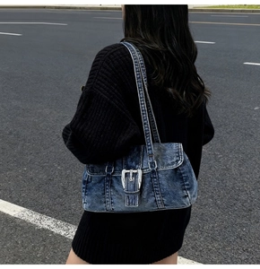 Gros plan du sac sous l'aisselle en denim bleu délavé avec boucle argentée et bretelles