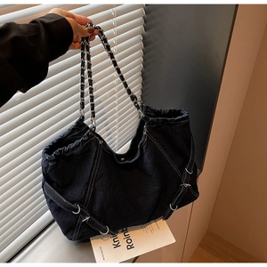 Detailed macro of vintage denim bag with woven metal chain strap and silver rings