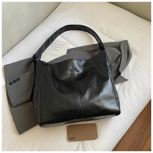 Detail view of a large black glossy patent leather tote bag with crinkled texture for women
