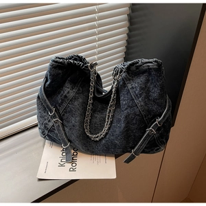Detail view of washed denim texture with drawstring closure and silver chain strap