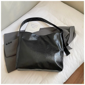 Detail of black glossy PU leather tote bag showing large capacity and smooth texture