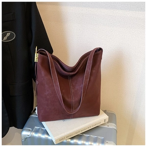 Detail der burgunderroten Wildledertasche mit Kontrastnähten und goldener Hardware