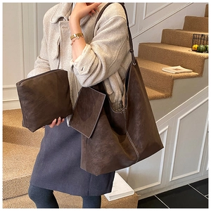 Close-up of brown suede shoulder bag set with stylish contrast white stitching detail