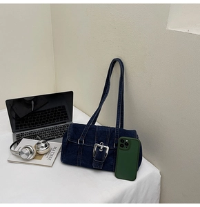 Détail du sac à épaule en jean bleu avec sangles verticales et boucle carrée argentée