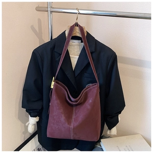Detail der burgunderroten Veloursleder-Tasche mit weißen Kontrastnähten und Goldschnalle