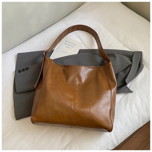 Detail of vintage brown tote bag with oily leather texture and vertical stitch on grey suit