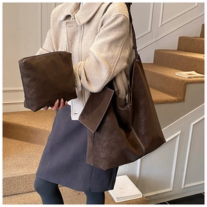 Detail view of brown suede tote bag set with white contrast stitching in a cozy indoor setting