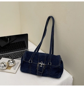 Détail du sac baguette en denim indigo foncé avec une grande boucle métallique argentée
