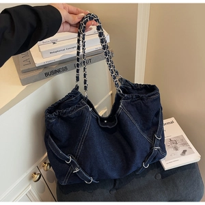 Detailed macro of vintage dark blue denim tote bag with contrast stitching and metal chain