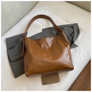 Macro detail of brown leather tote bag with smartphone showing large storage capacity