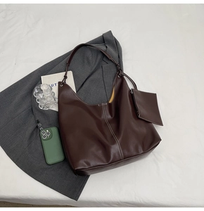 Détail du sac hobo en cuir mat marron foncé avec coutures blanches et mini pochette