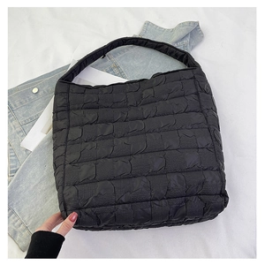 Detail of black quilted tote bag with bubble textured fabric and wide shoulder strap