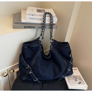 Detail of dark blue washed denim shoulder bag featuring side buckle and chain strap