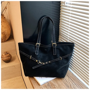 Detailopname van zwarte tote bag met witte contraststiksels en gouden metalen gesp detail