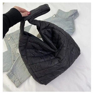 Detailed close-up of a black quilted tote bag showing textured nylon fabric and stitching