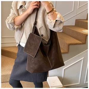 Detail of dark brown suede tote bag with contrast stitching and small pouch on stairs