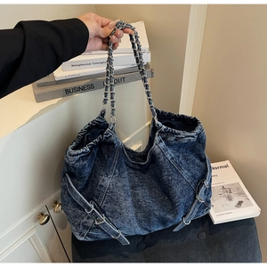 Detailed macro of vintage washed denim tote with silver metal chain straps and side buckles