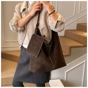 Detail view of large brown suede tote bag with contrast stitching and small charm pouch