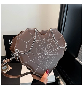 Detail der herzförmigen braunen Umhängetasche mit weißem Spinnennetz-Stich und Metallketten