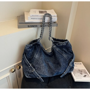 Detail view of the vintage washed denim tote bag featuring a metal chain handle and side buckles
