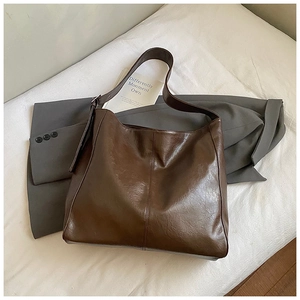 Detail of dark brown tote bag with pebble texture styled on a grey blazer suit