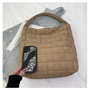 Detailed scale view of a khaki quilted tote bag with a phone for size comparison