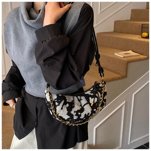 Detail of crescent shoulder bag with jacquard pattern and decorative gold chain