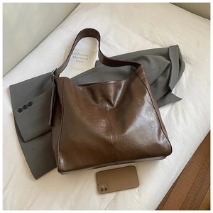 Detailed top view of large brown vintage leather tote bag on white fabric background