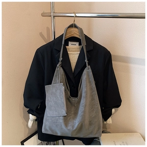 Detail of grey suede tote bag with contrast stitching and matching mini zipper pouch
