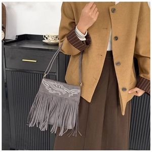 Bolso de hombro en ante gris con flecos y bordados mostrado en una sesión de fotos