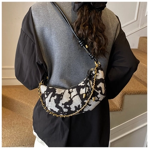 Detail of crescent crossbody bag with black and white jacquard pattern and gold chain strap