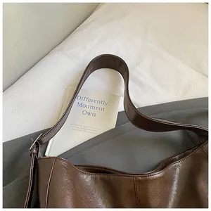 Deep brown glossy PU leather hobo bag on a minimalist bed setting with a vintage vibe
