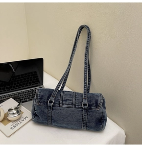 Détail d'un sac à bandoulière cylindrique en denim bleu délavé avec boucles métalliques