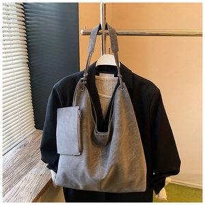 Detail view of large grey tote bag with knot strap and matching pouch on hanger