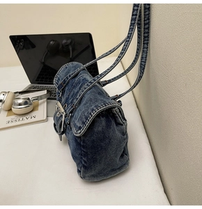 Détail du sac bandoulière en denim délavé avec boucle argentée et texture vintage Y2K