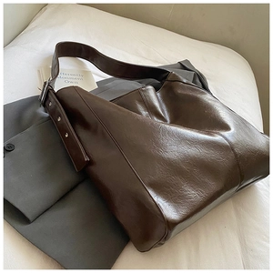 Detailed view of the dark brown oil-leather texture and strap of a large hobo tote bag