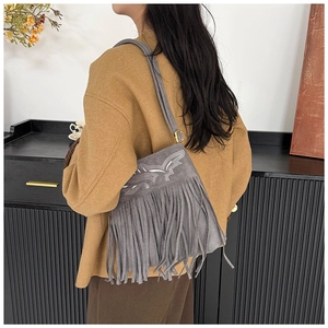 Vista detallada del bolso de gamuza gris con bordados y flecos largos decorativos