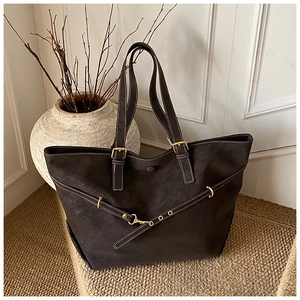 Detail van vintage donkerbruine shopper met witte stiksels en gouden metalen gesp